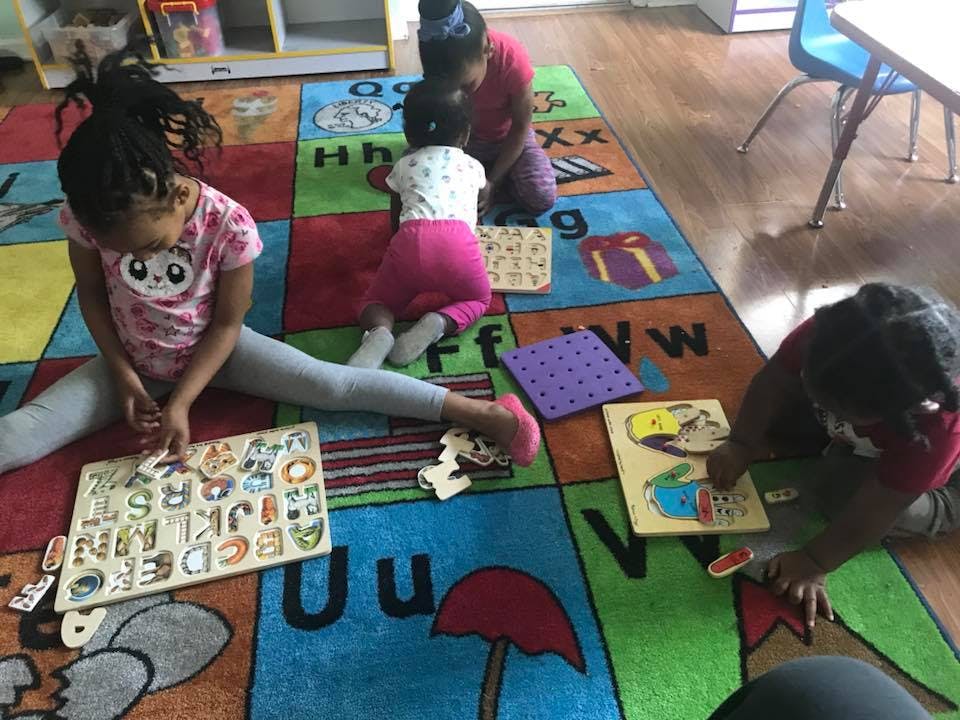 Children playing with puzzles on a colorful alphabet rug