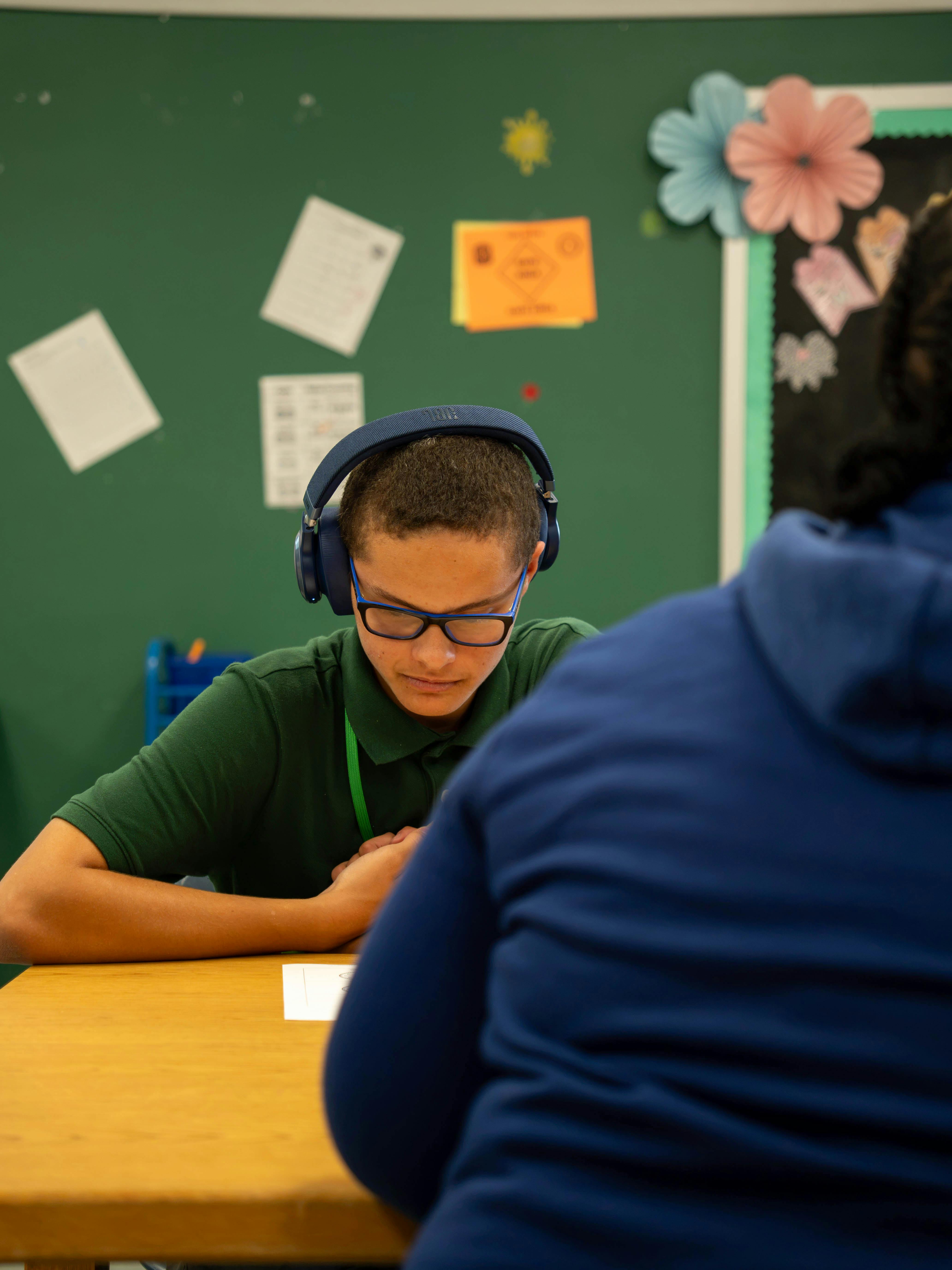 Student wearing headphones at a desk in a classroom