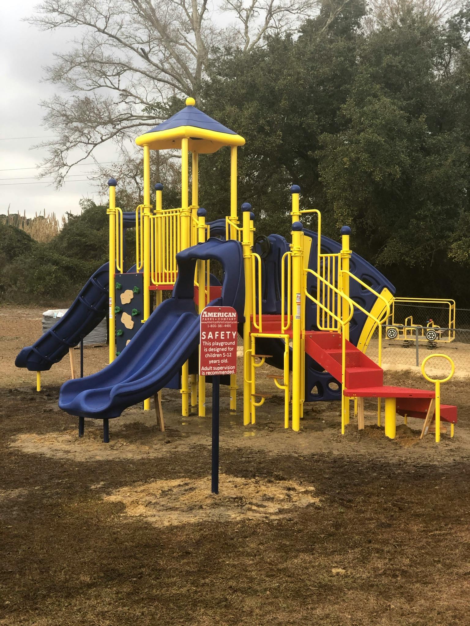 Playground structure with slides and stairs, with a safety sign