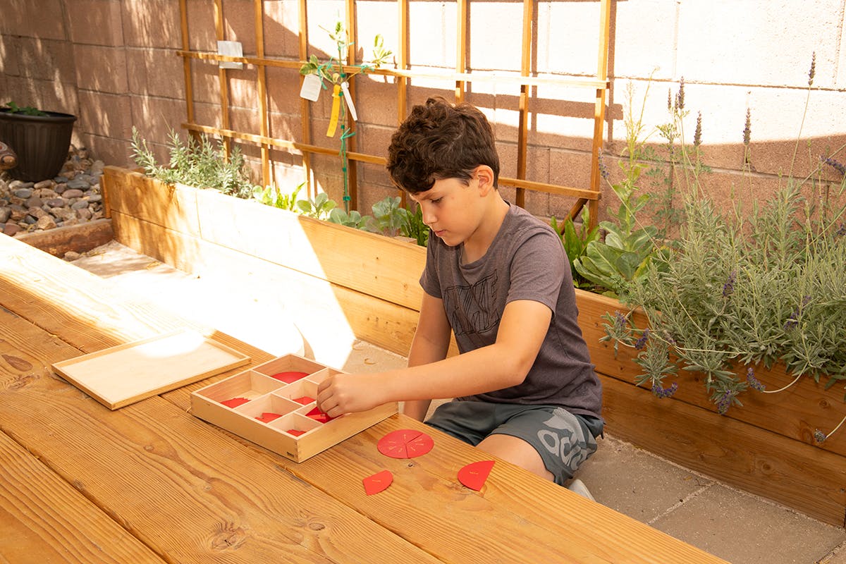 Child playing with red shapes on a wooden table