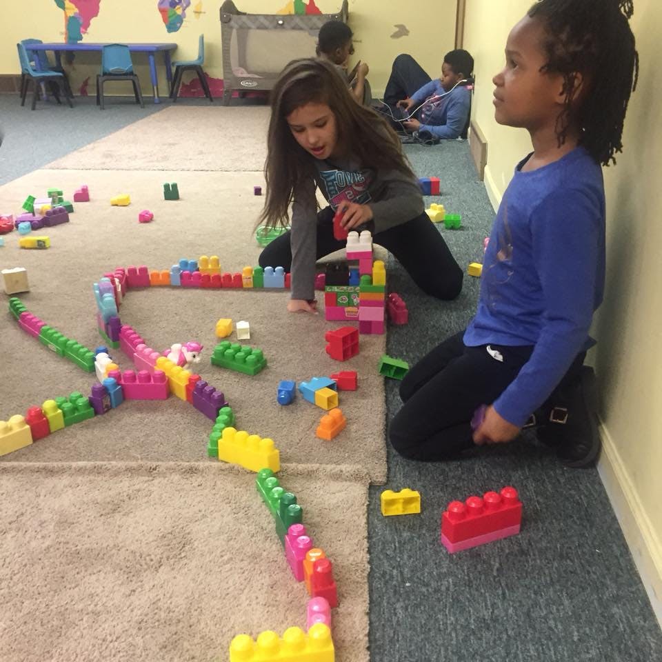 Two children playing with colorful building blocks on the floor
