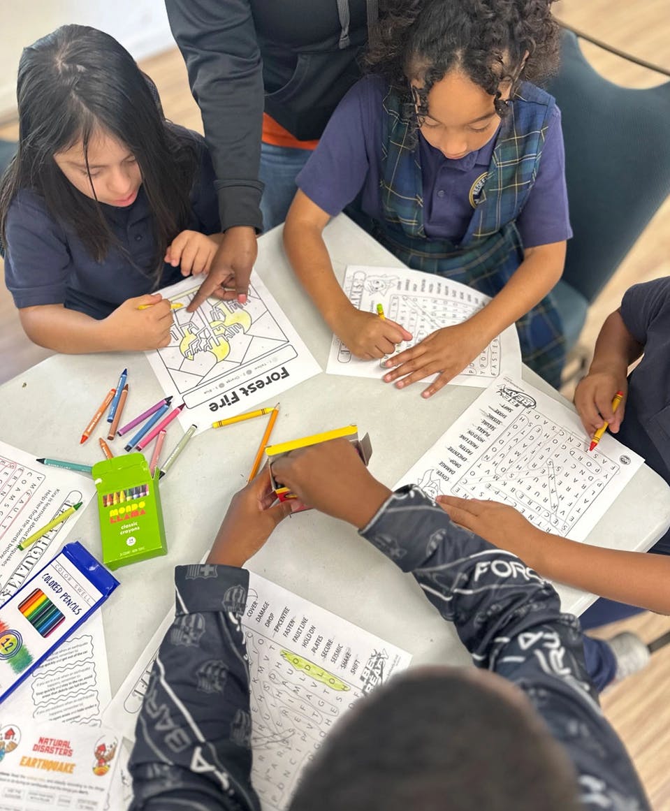 multiple children coloring 'Forest Fire' and 'Natural Disasters' activity sheets