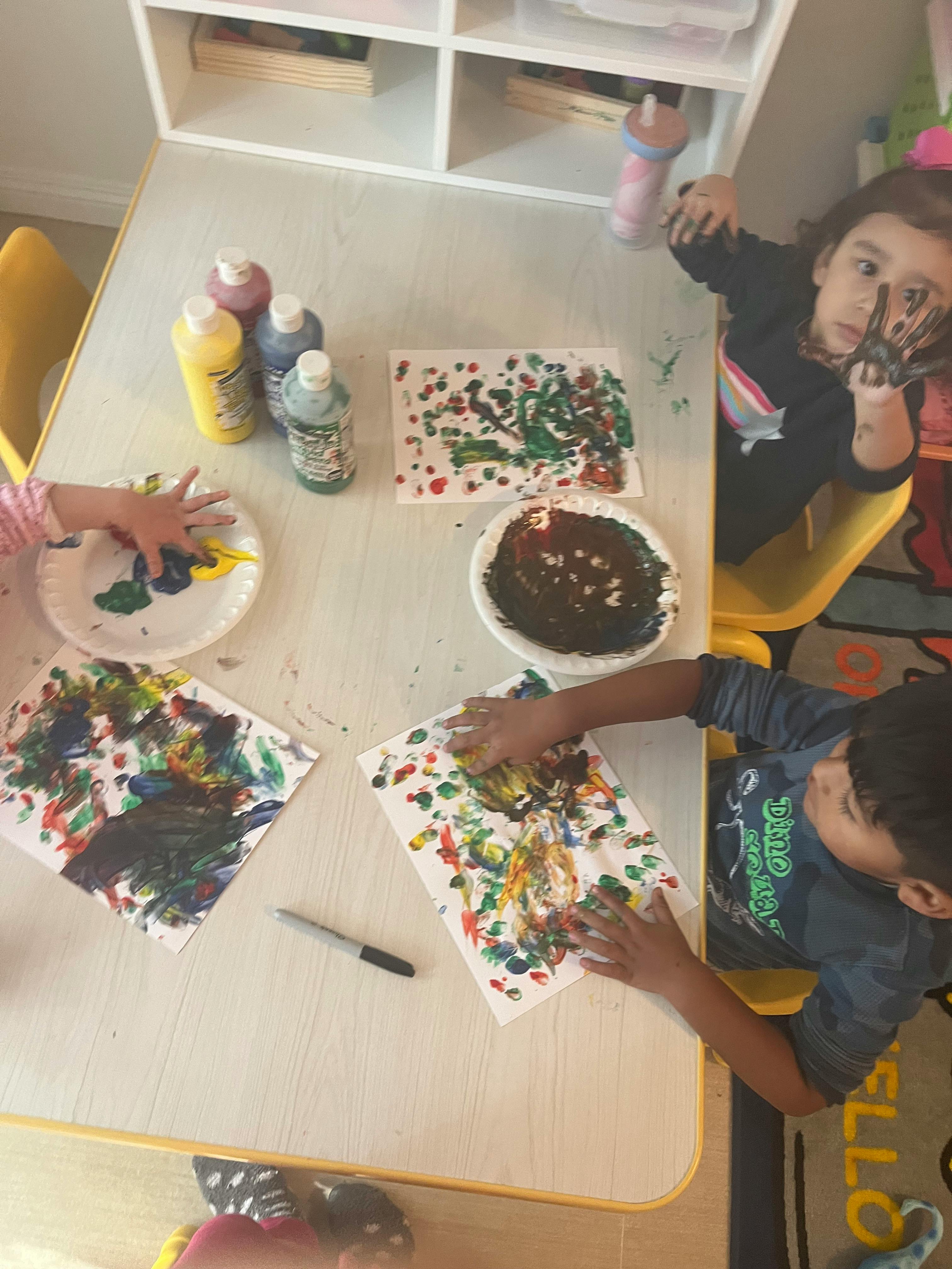 Children finger painting at a table