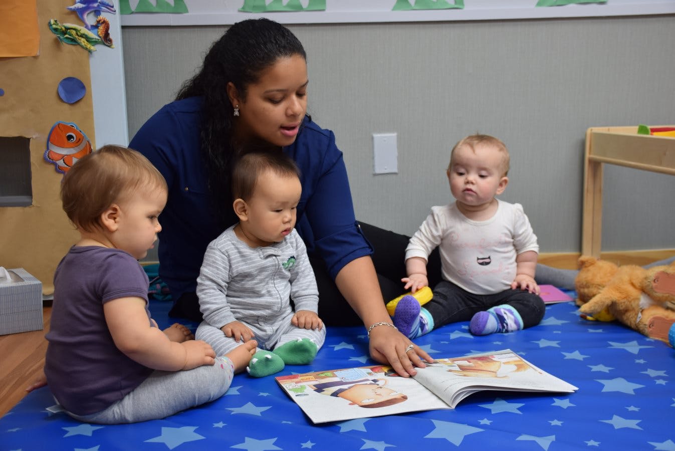 Person reading a book to three children