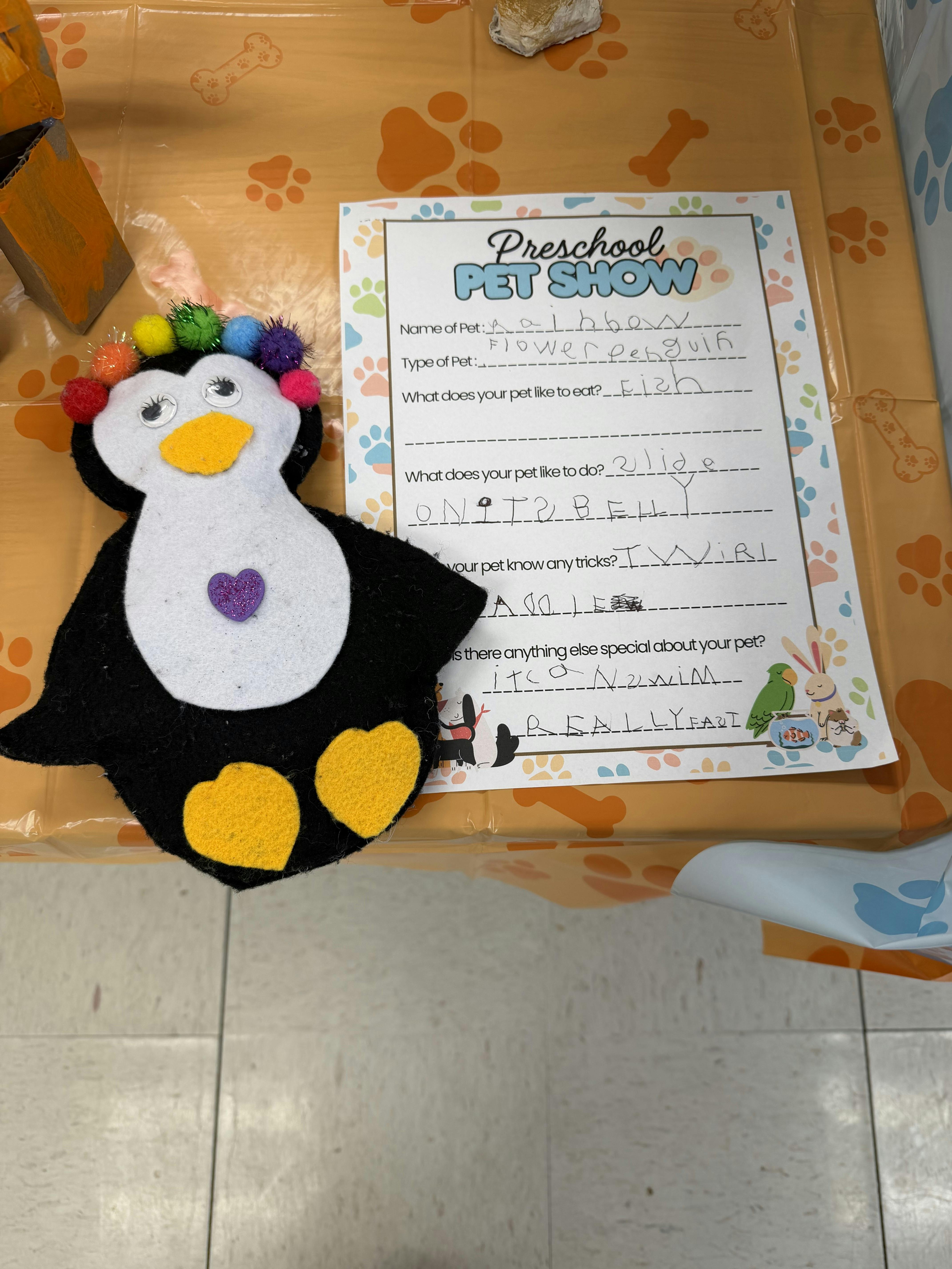 A Preschool Pet Show form with a felt penguin toy wearing a colorful pom-pom crown