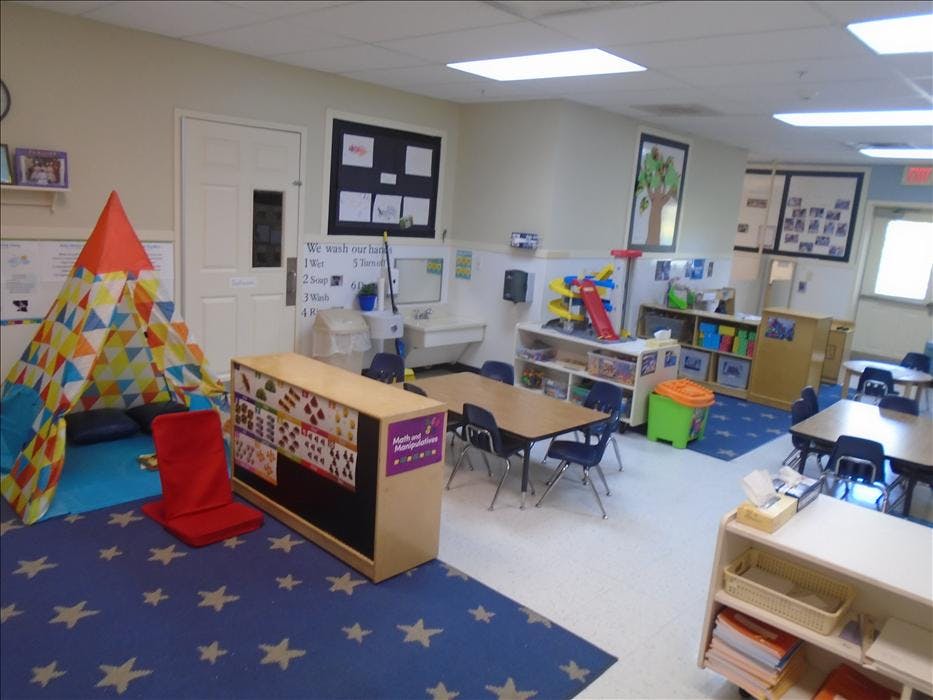 Classroom with tables, chairs, colorful play tent, and a sink