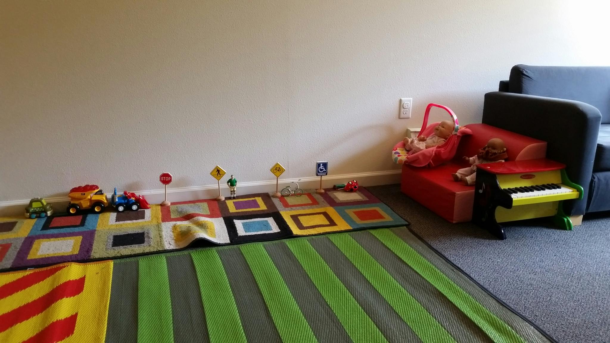 Play area with toy trucks, road signs, and a colorful rug