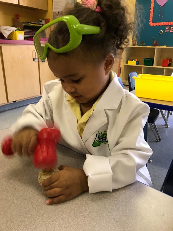 Child in a lab coat and goggles playing with a toy