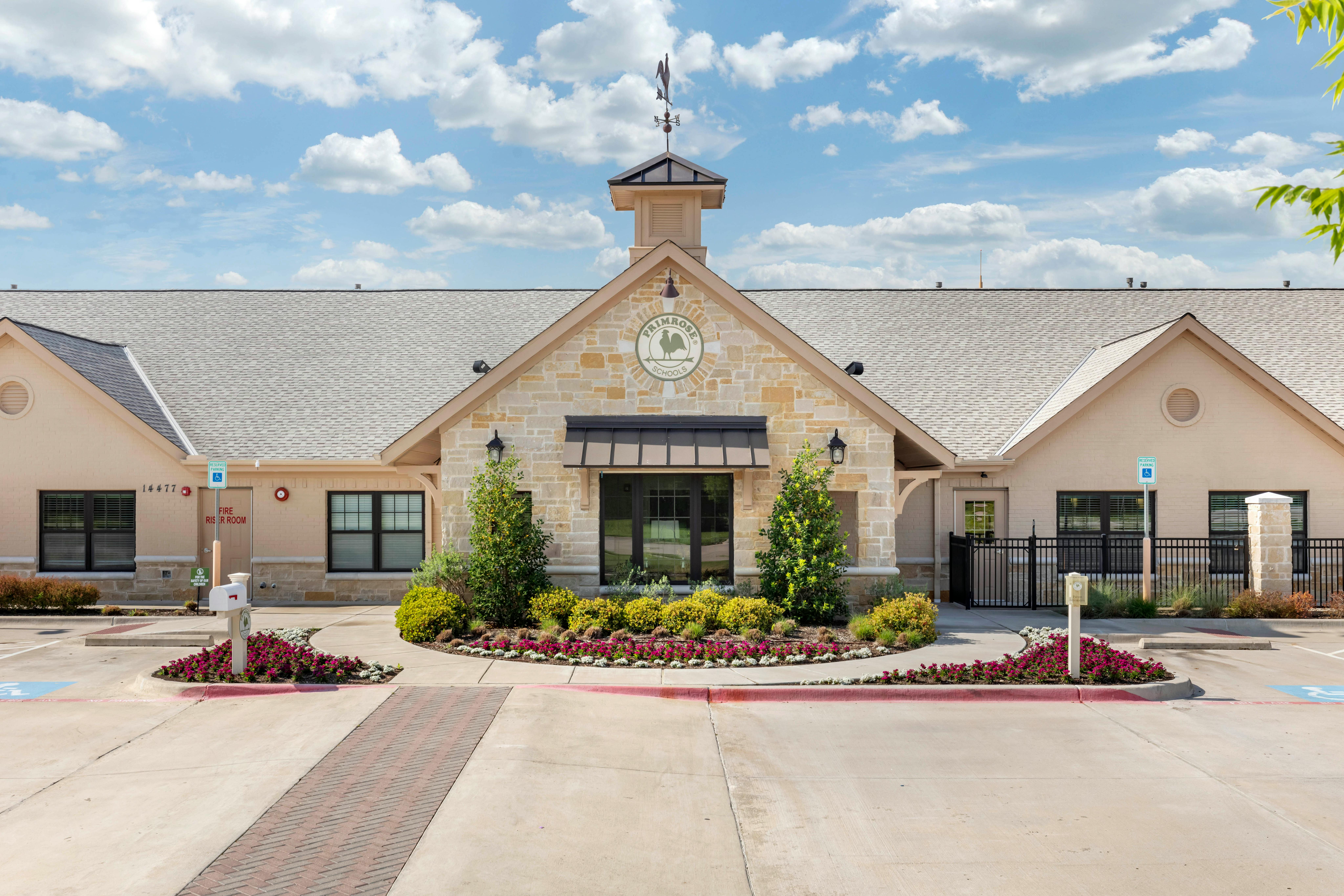 Primrose School building with stone facade, cupola, and landscaped entrance