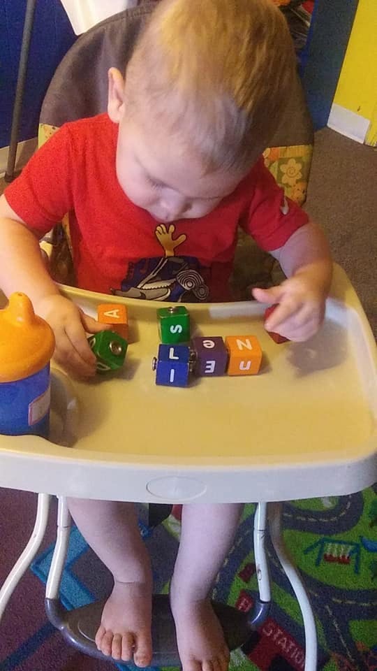Child in a high chair playing with alphabet blocks