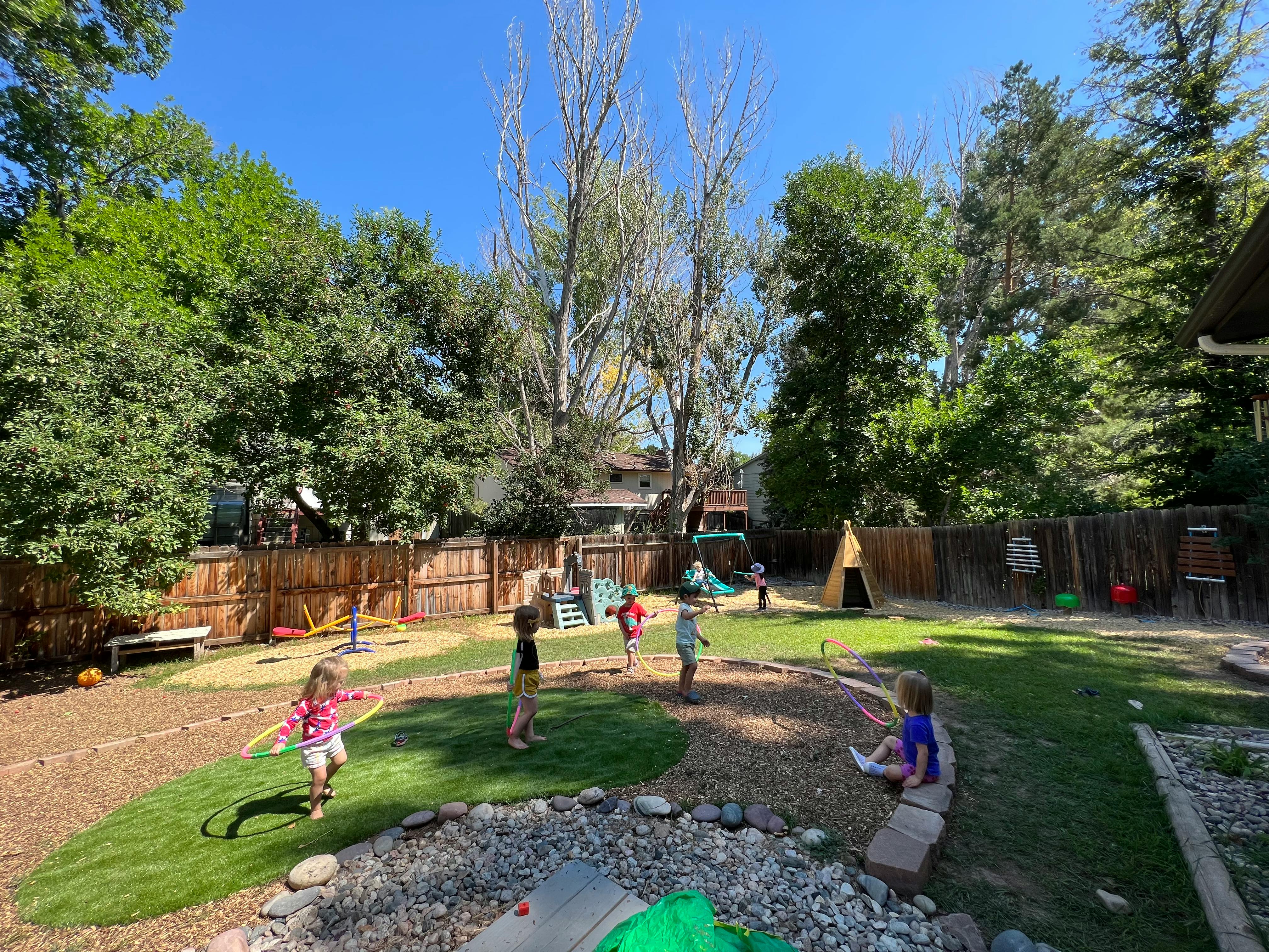 Children playing in a backyard with grass and wood chips