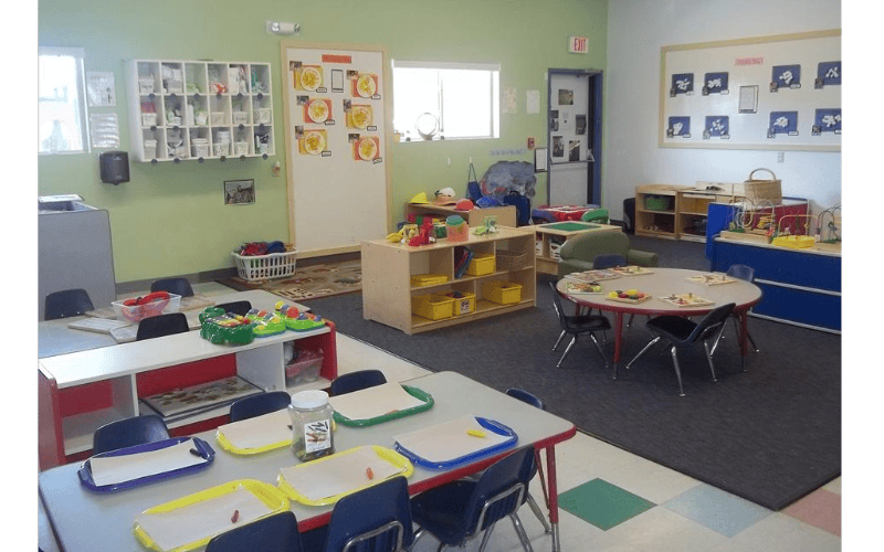 A colorful classroom with child-sized tables, chairs, and play areas