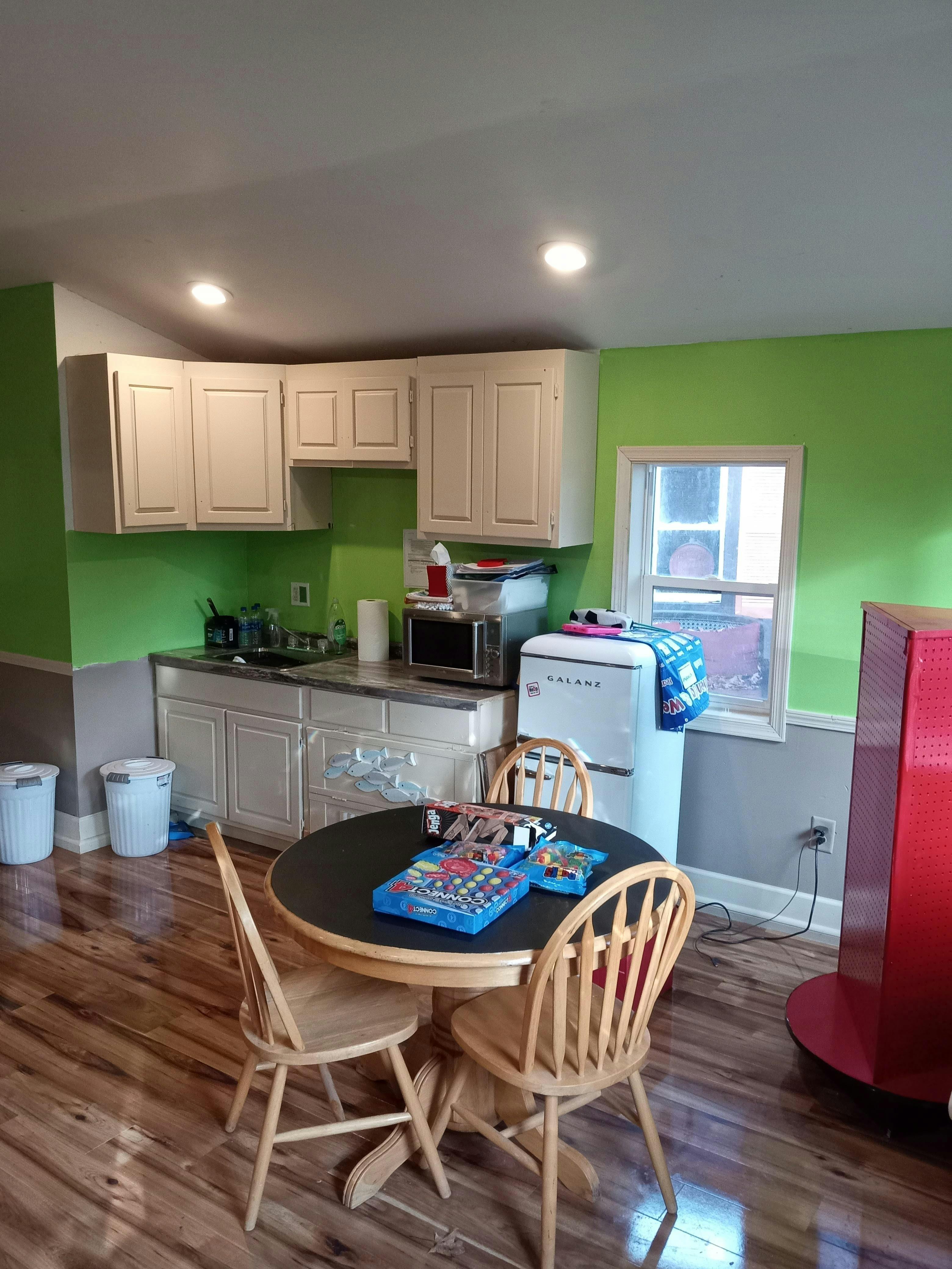 Kitchen with green walls, white cabinets, and a round dining table