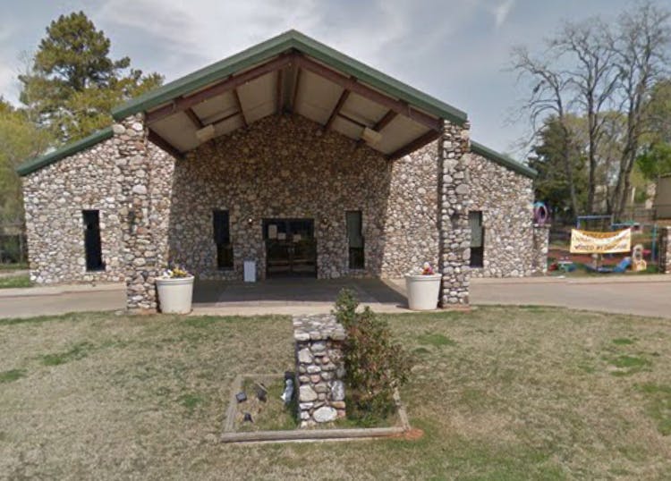 Stone building with a covered entrance and a grassy foreground