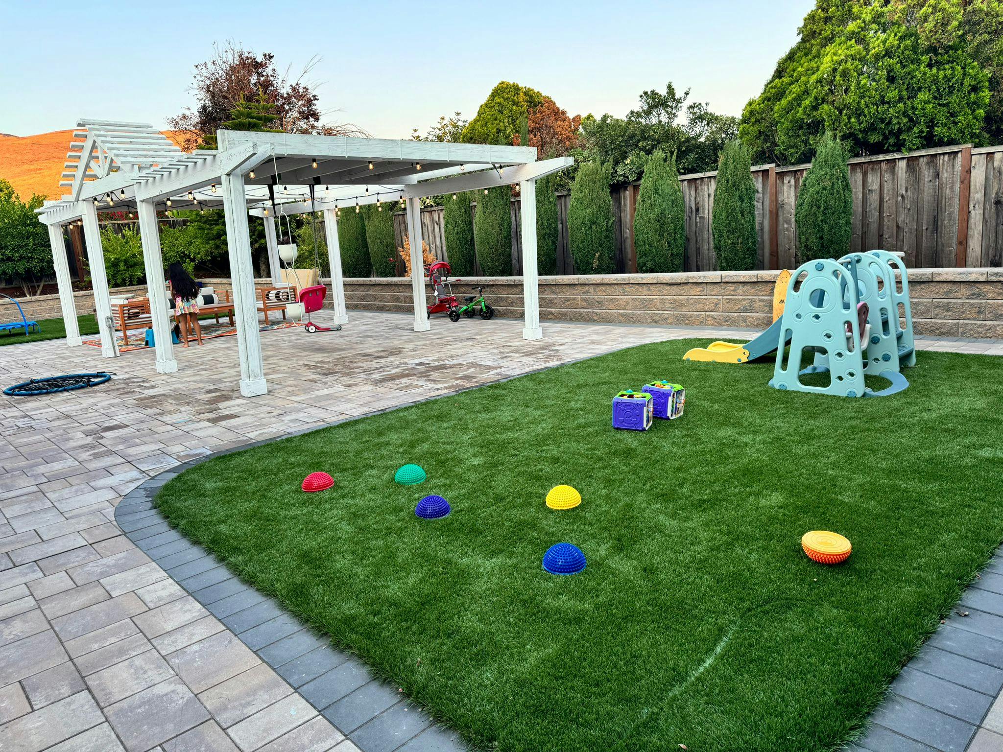Backyard with a pergola, patio, and lawn with children's play equipment
