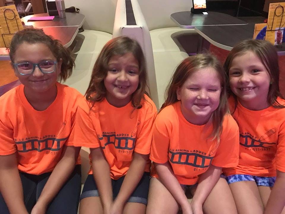 Four children in orange shirts sitting together
