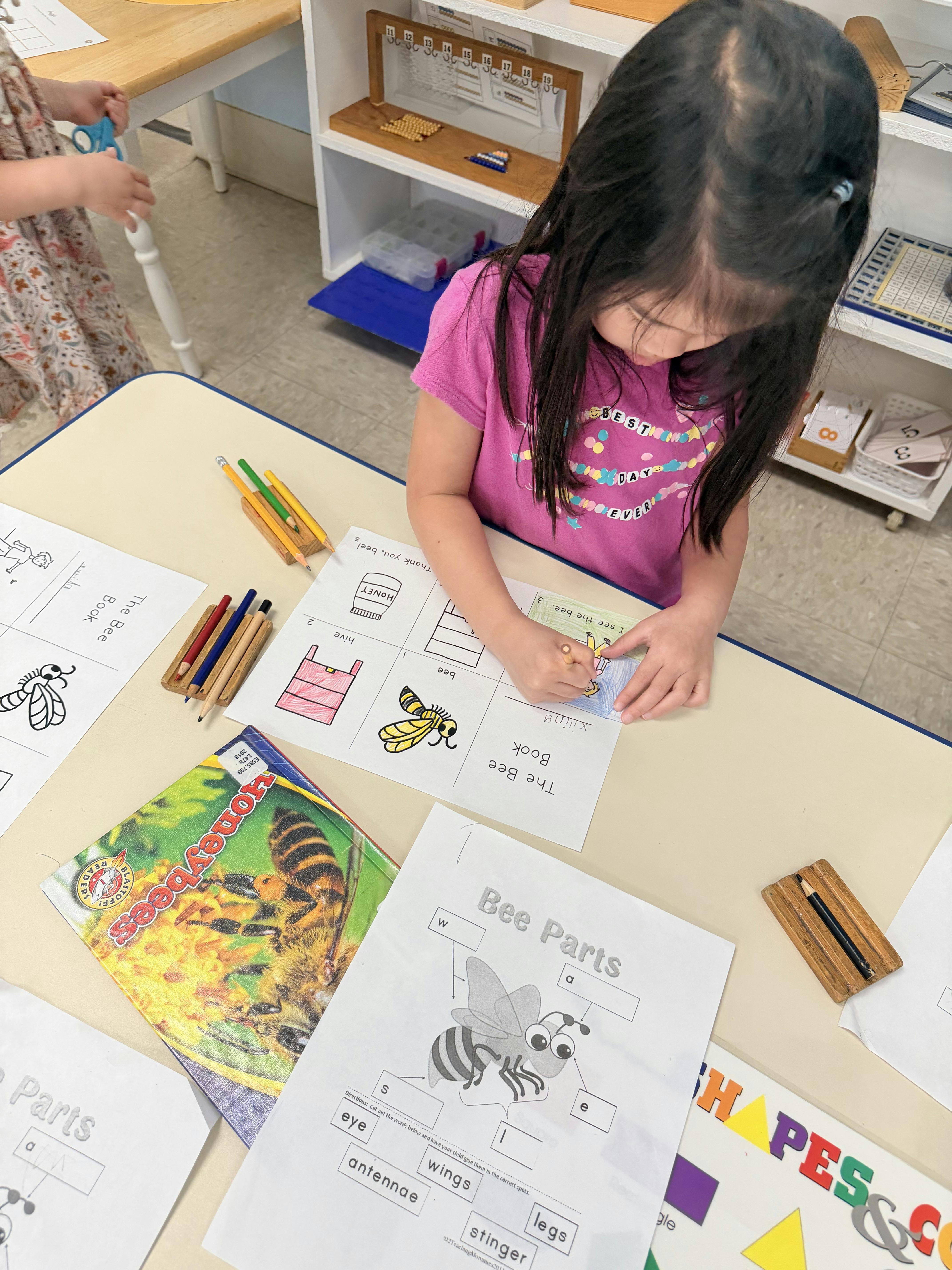 Child coloring a bee-themed worksheet in a classroom