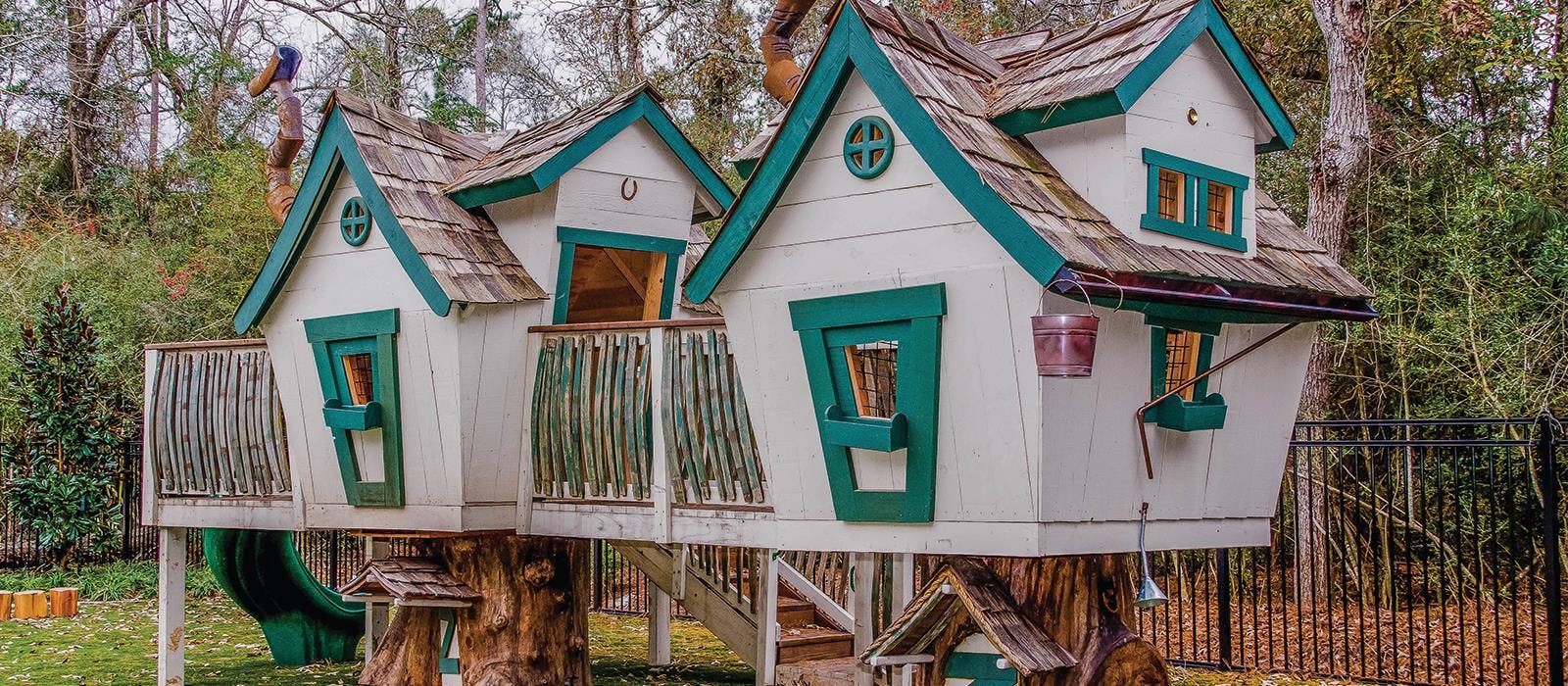 White and green multi-level treehouse with a slide