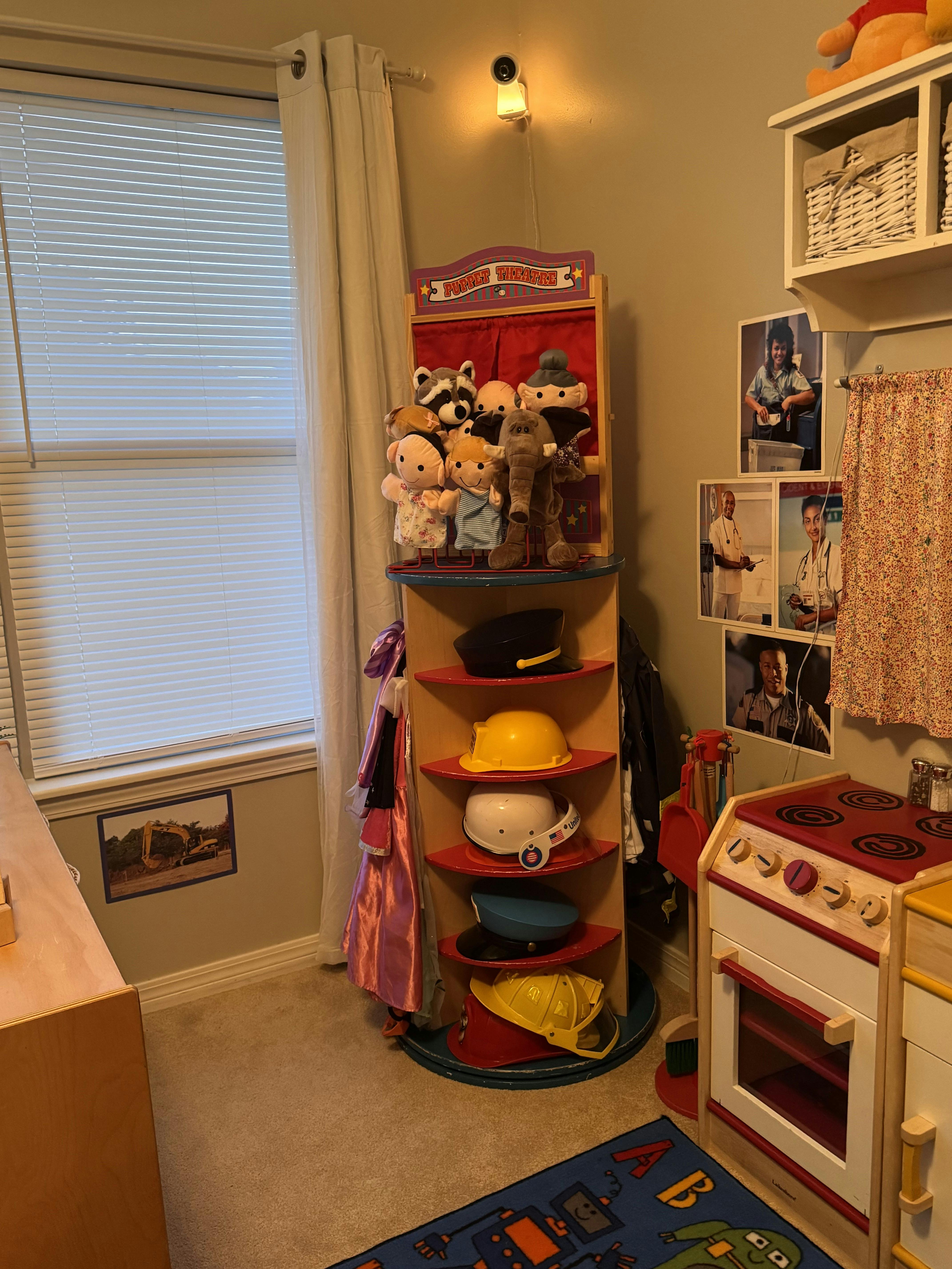 Play area with a puppet theatre and shelves filled with toy hats and costumes