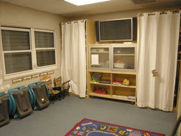 Classroom with backpacks, shelves, and a television