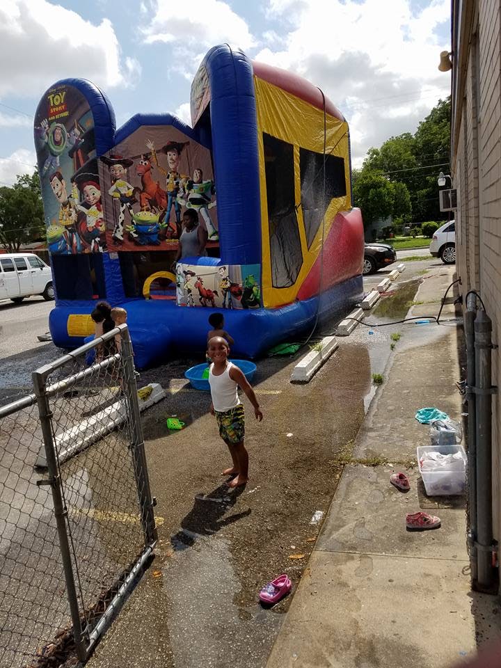 Child standing on wet pavement in front of a large inflatable bounce house