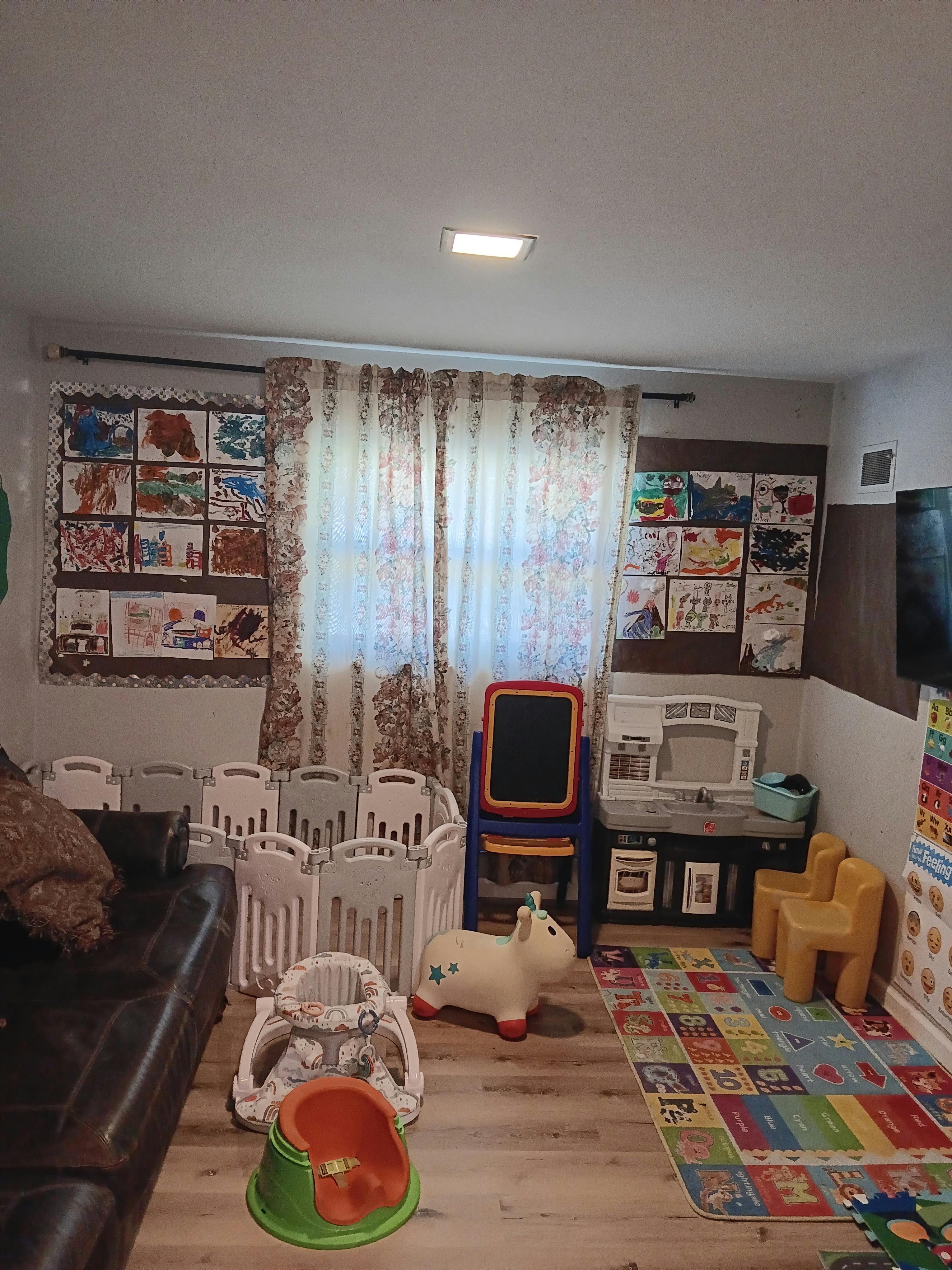 Playroom with a playpen, easel, toy kitchen, and colorful rug
