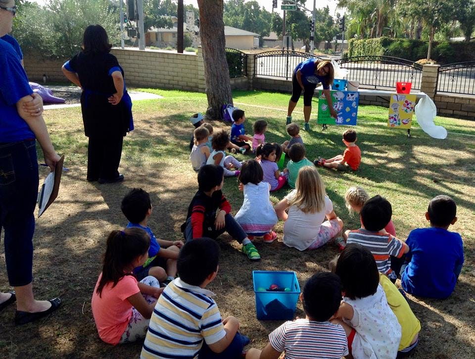 Adults and children sitting on the ground outdoors