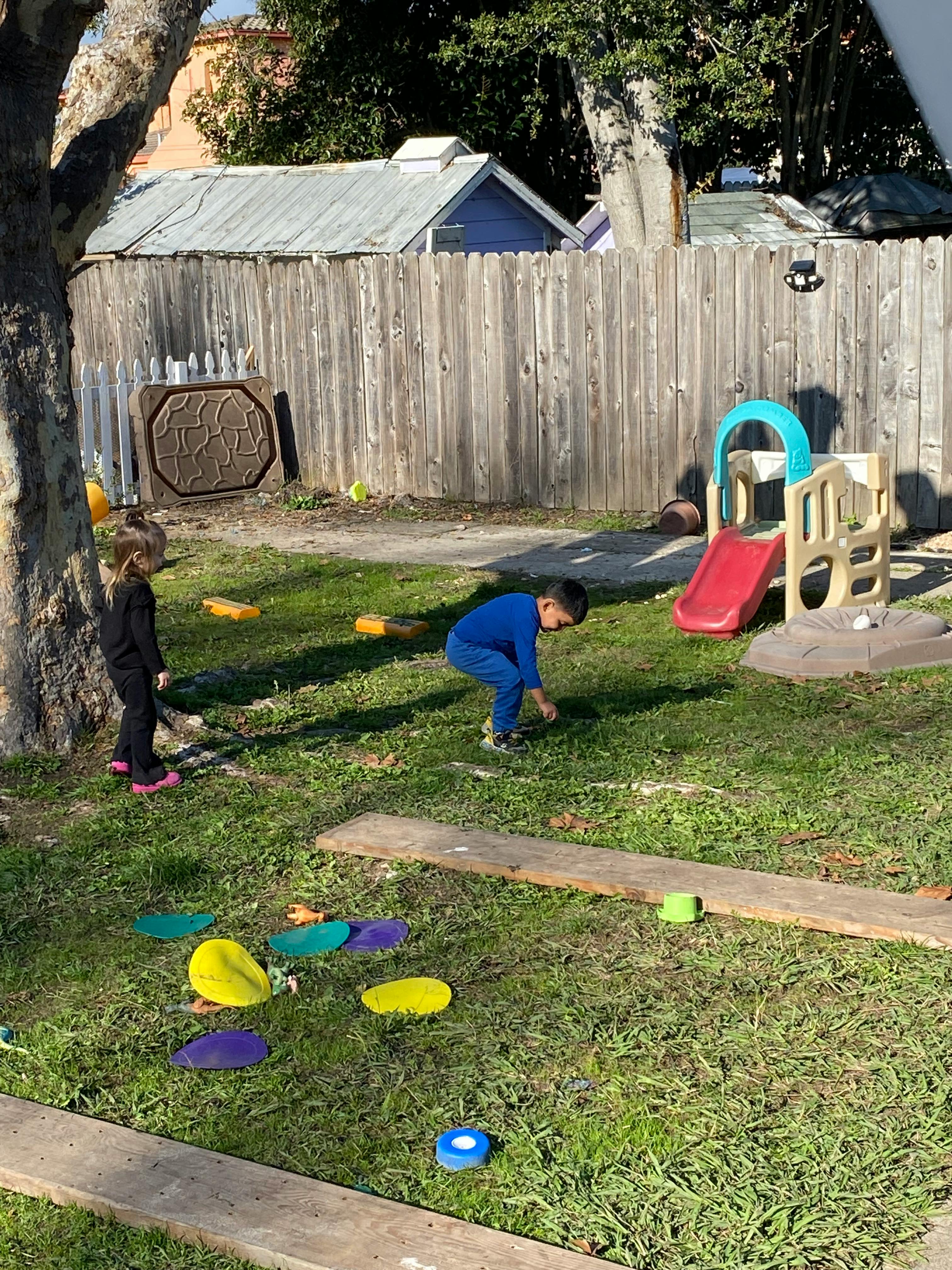 Two children playing in a grassy yard with a small slide