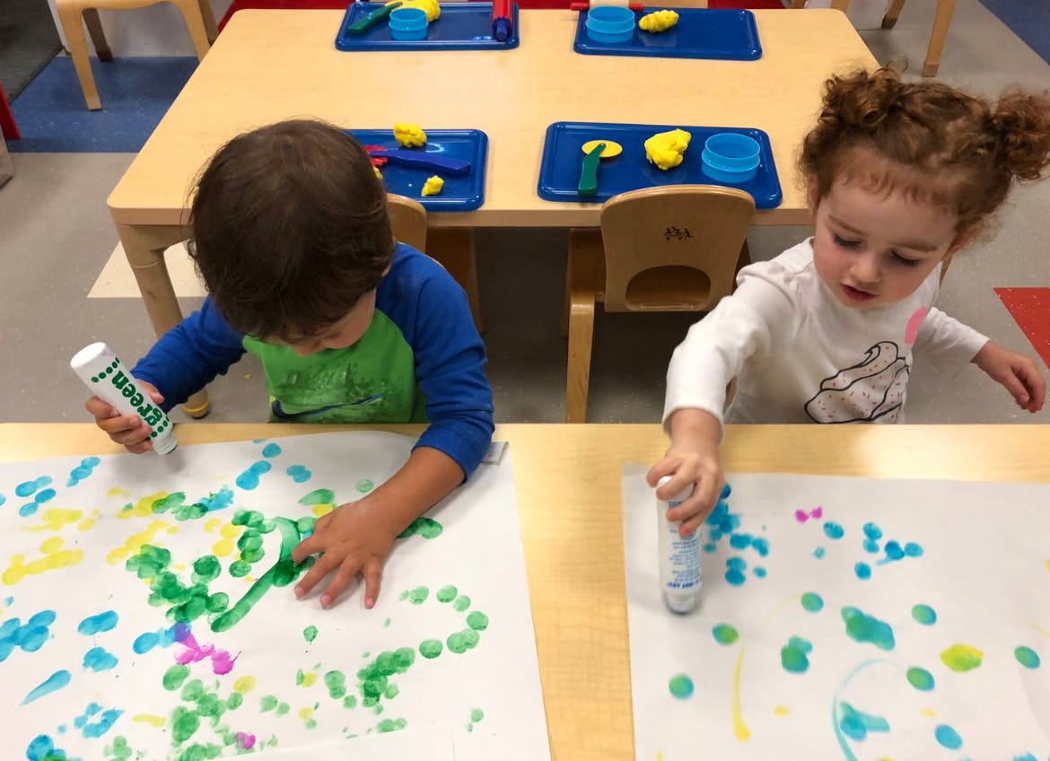 Two children painting with dot markers at a table