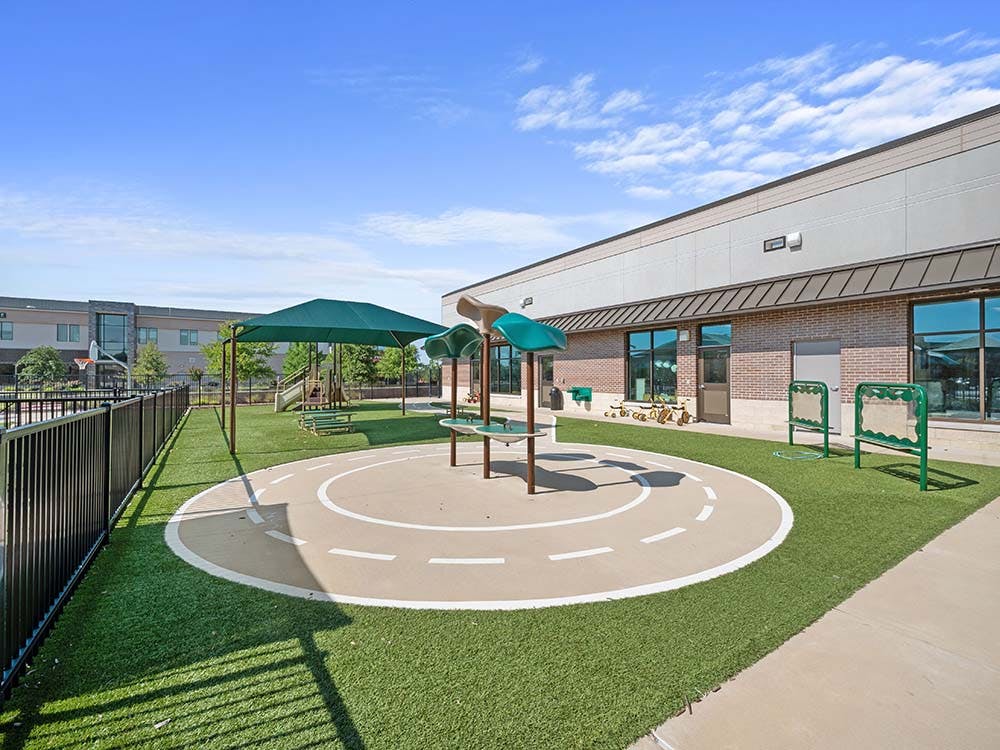 Outdoor playground area with artificial turf, play equipment, and a small track