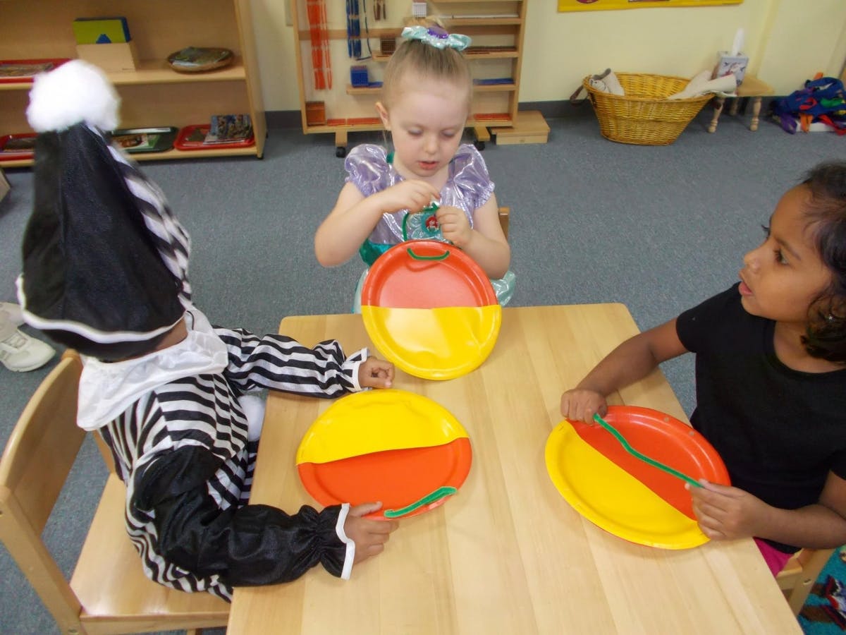 Three children playing with colorful toys at a table in a classroom