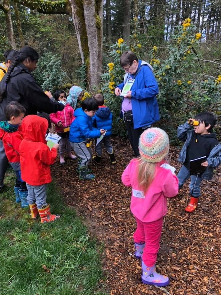 Adults and children gathered outdoors, looking at papers