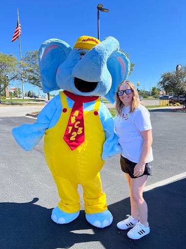 Person standing next to an elephant mascot