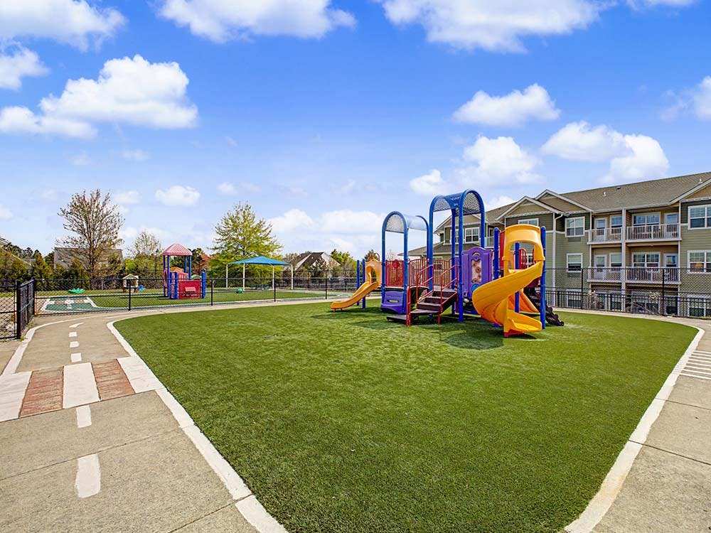 Colorful playground with slides and climbing structures on green turf next to a building