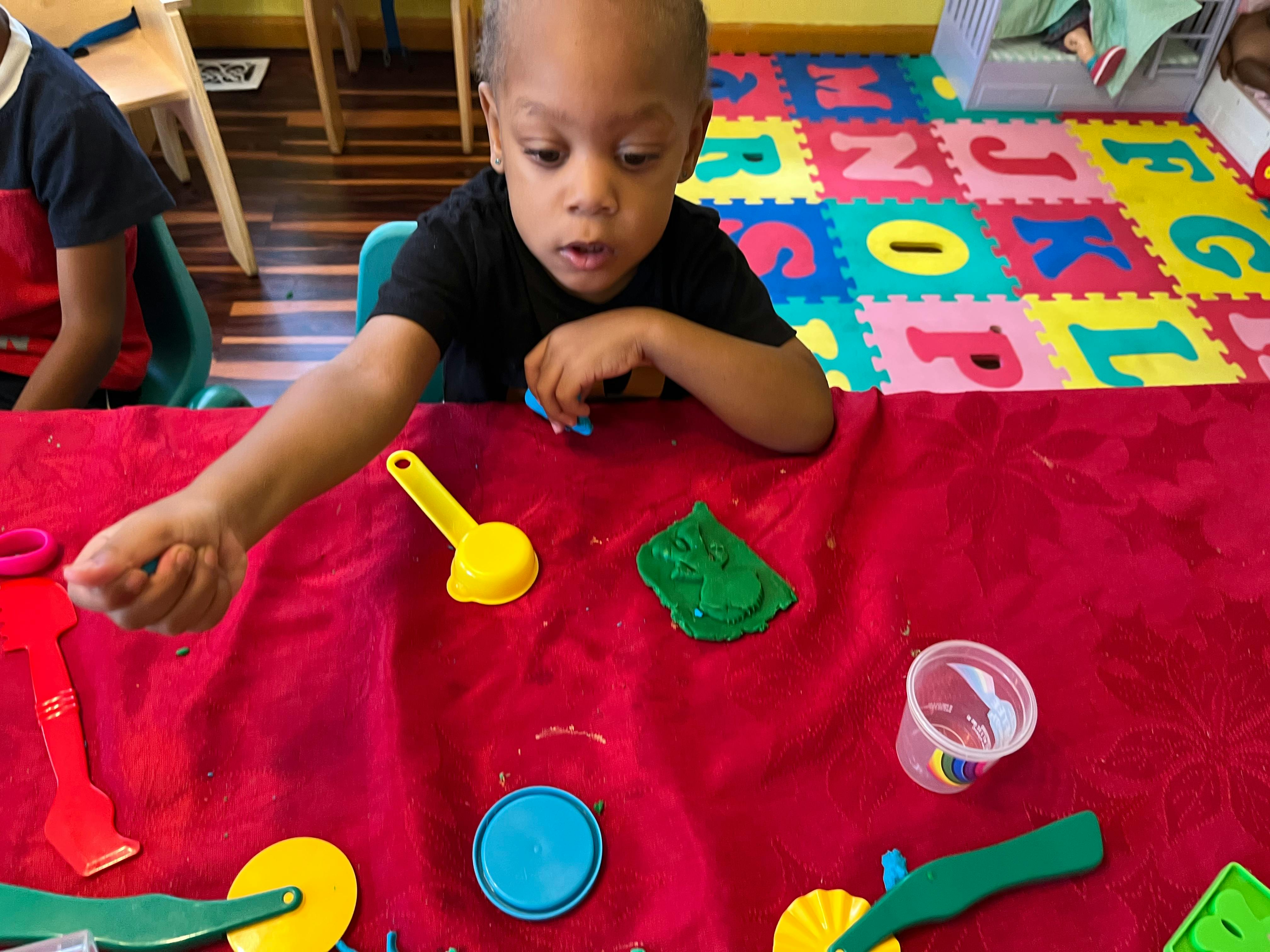 Child playing with modeling clay and tools at a table
