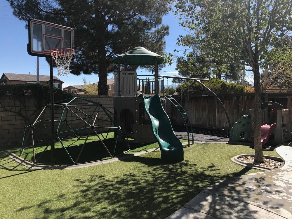 Playground with a slide, climbing dome, and basketball hoop