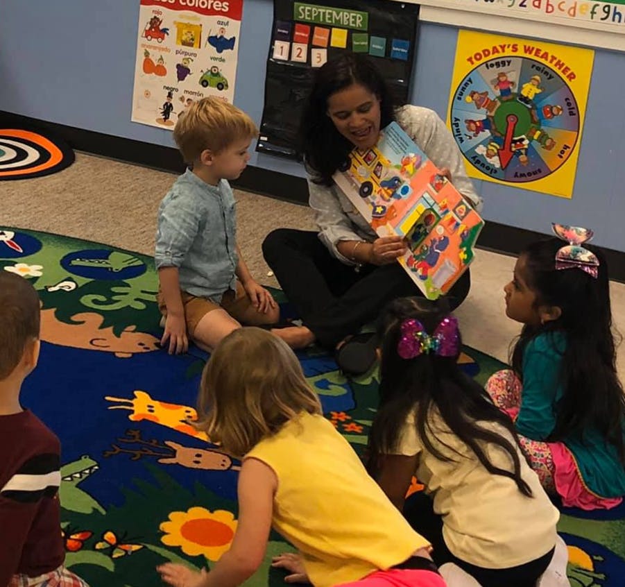 Person reading a book to children in a classroom