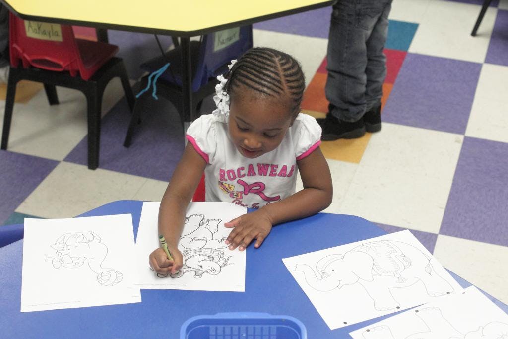 Child coloring at a table in a classroom
