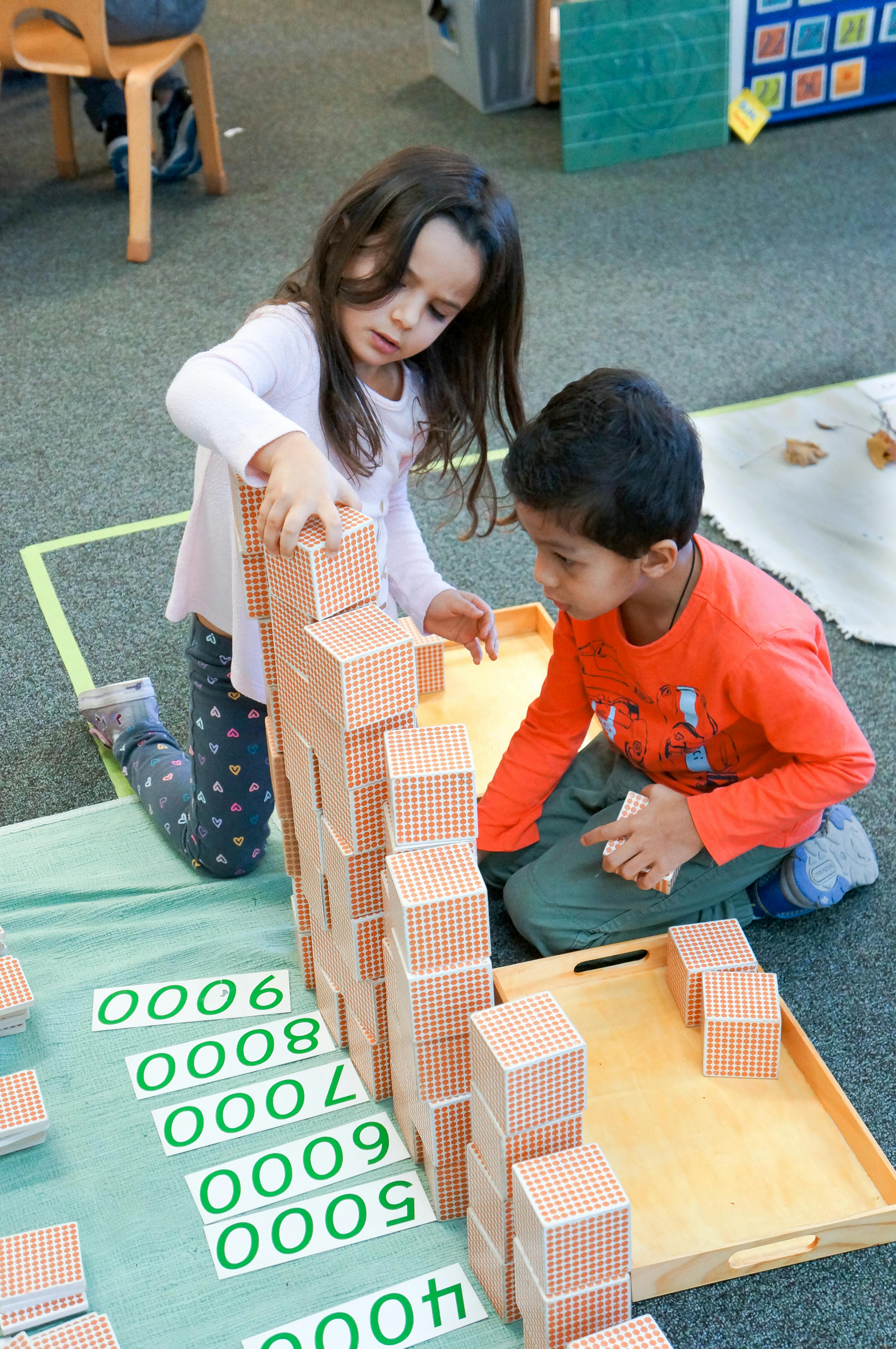 Two children building with blocks on the floor