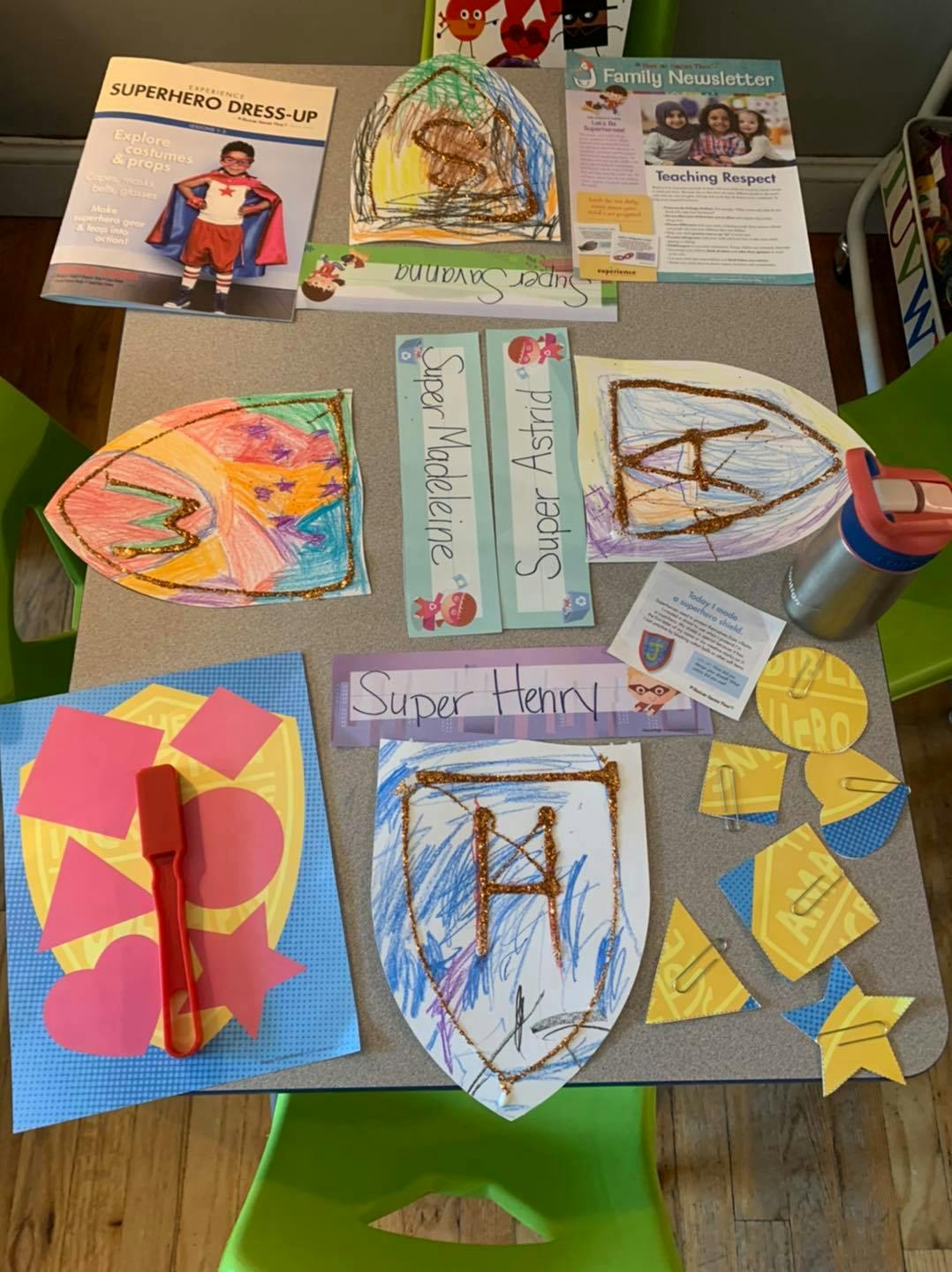 Tabletop with various children's craft projects, including shields and superhero-themed items
