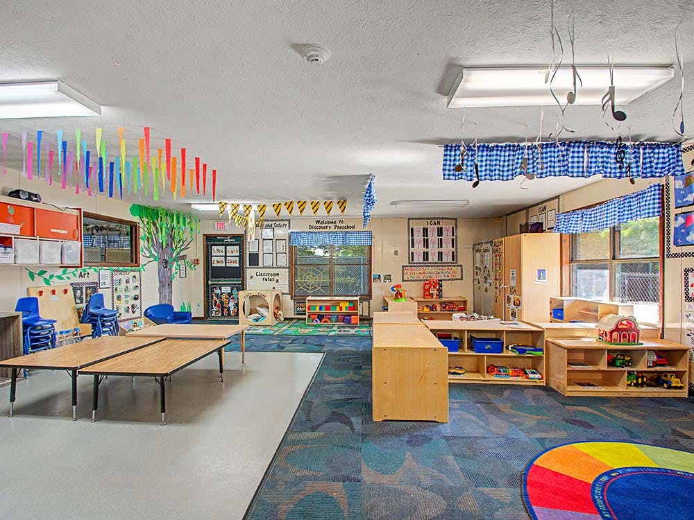 Colorful and organized classroom with tables, chairs, and shelves of learning materials