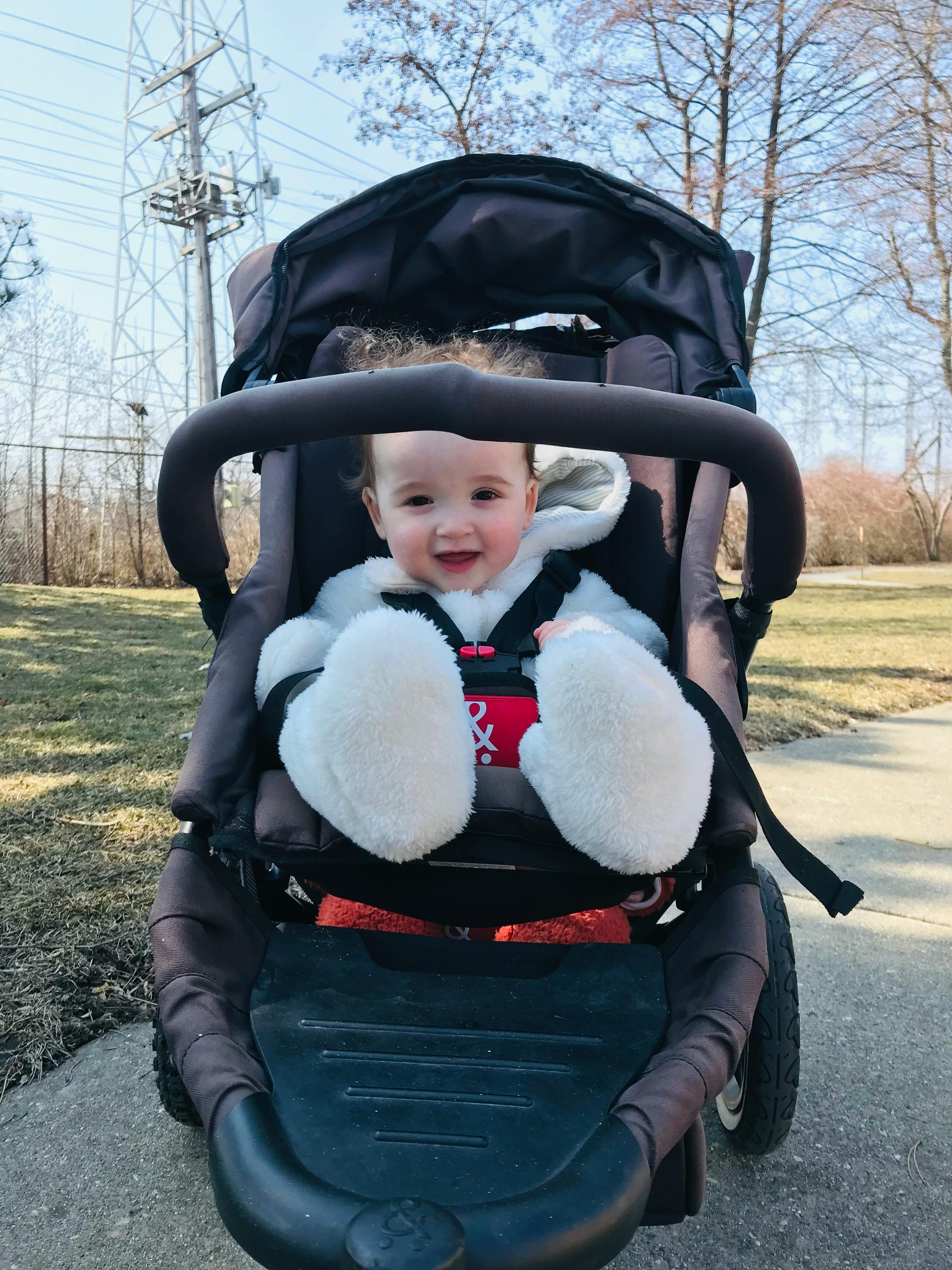 Child in a stroller wearing white mittens