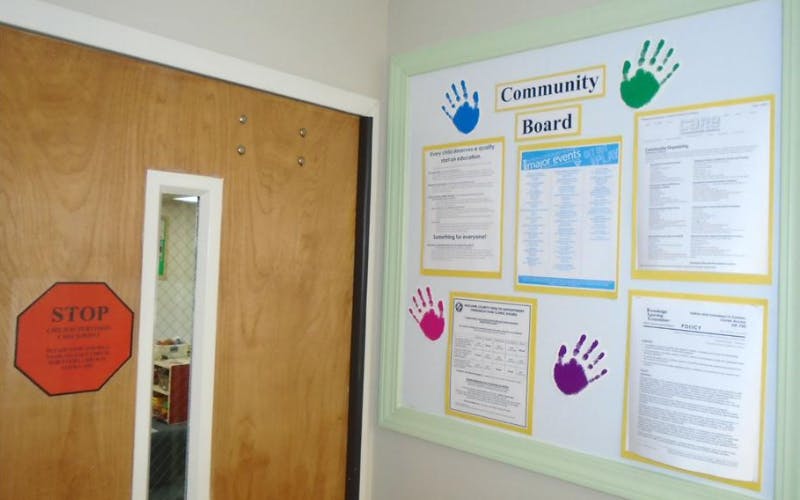 A wooden door with a "STOP" sign and a community board with papers