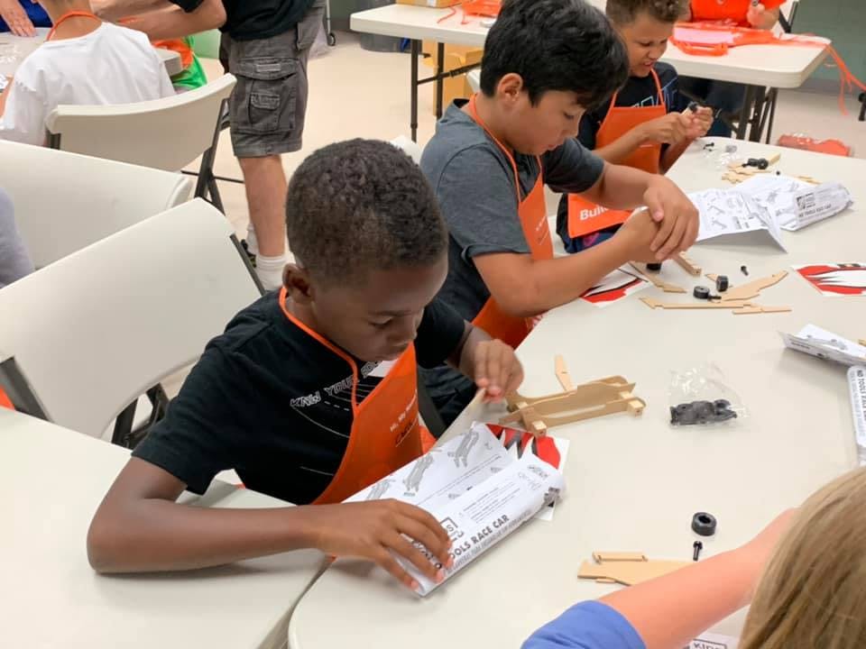 Children in aprons working on crafts at a table