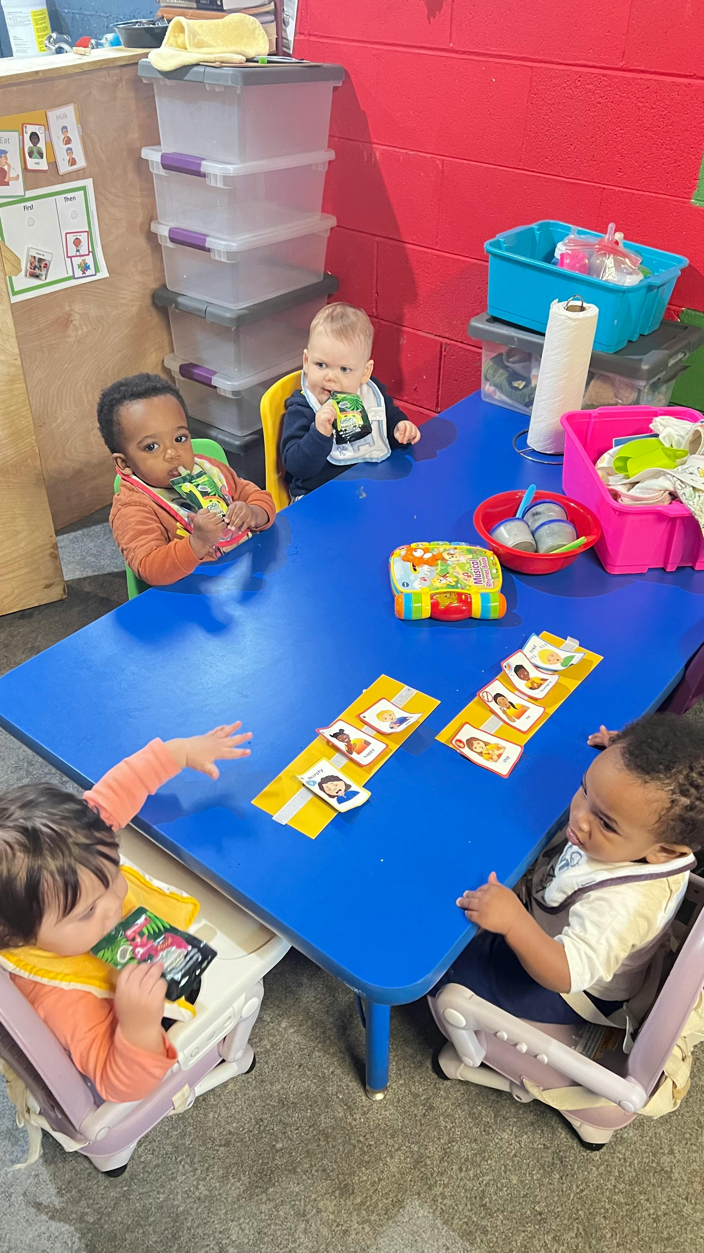 Four children sitting at a blue table in a classroom