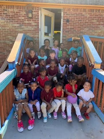 Group of children and adults sitting on outdoor stairs