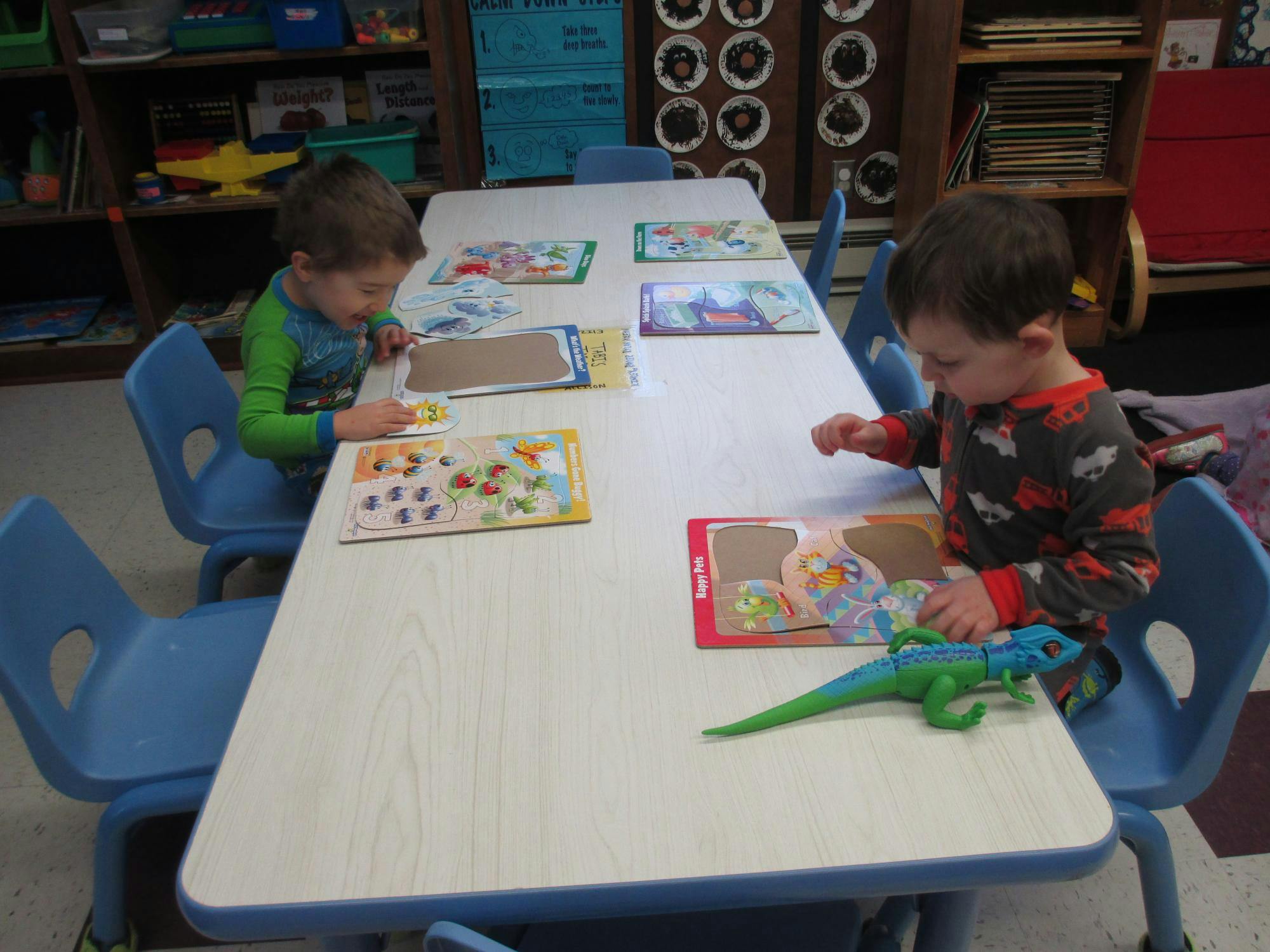 Two children sitting at a table playing with puzzles