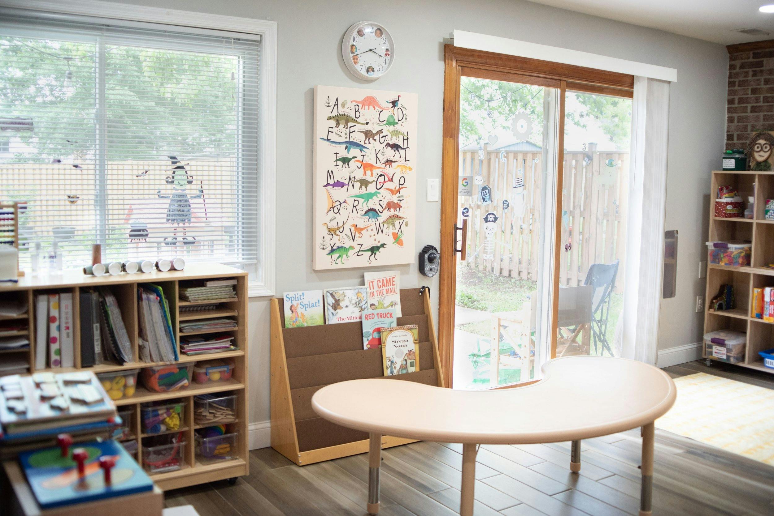Classroom with a kidney-shaped table, bookshelves, and a sliding glass door