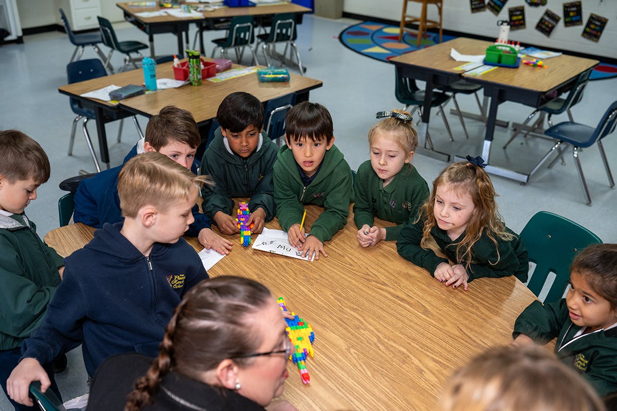 Children and an adult gathered around a table in a classroom