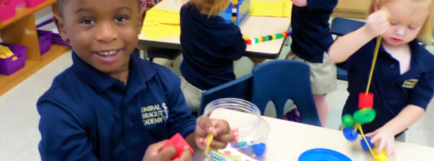 Child playing with beads and string at a table